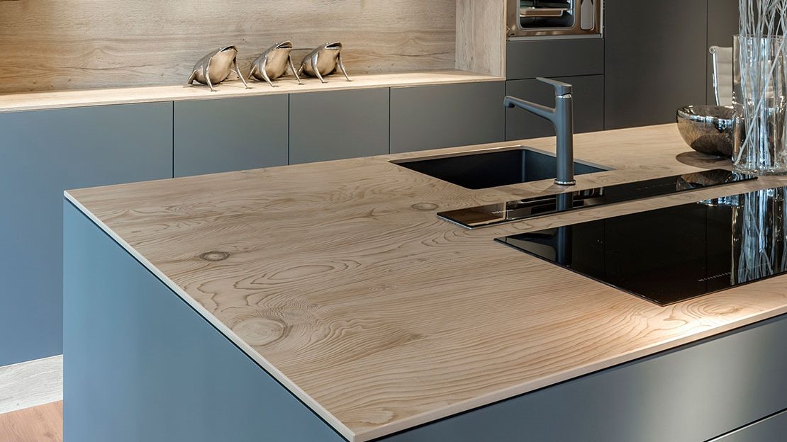 Îlot de cuisine avec plan en Neolith La Bohème effet bois clair, façades bleu-gris et évier intégré